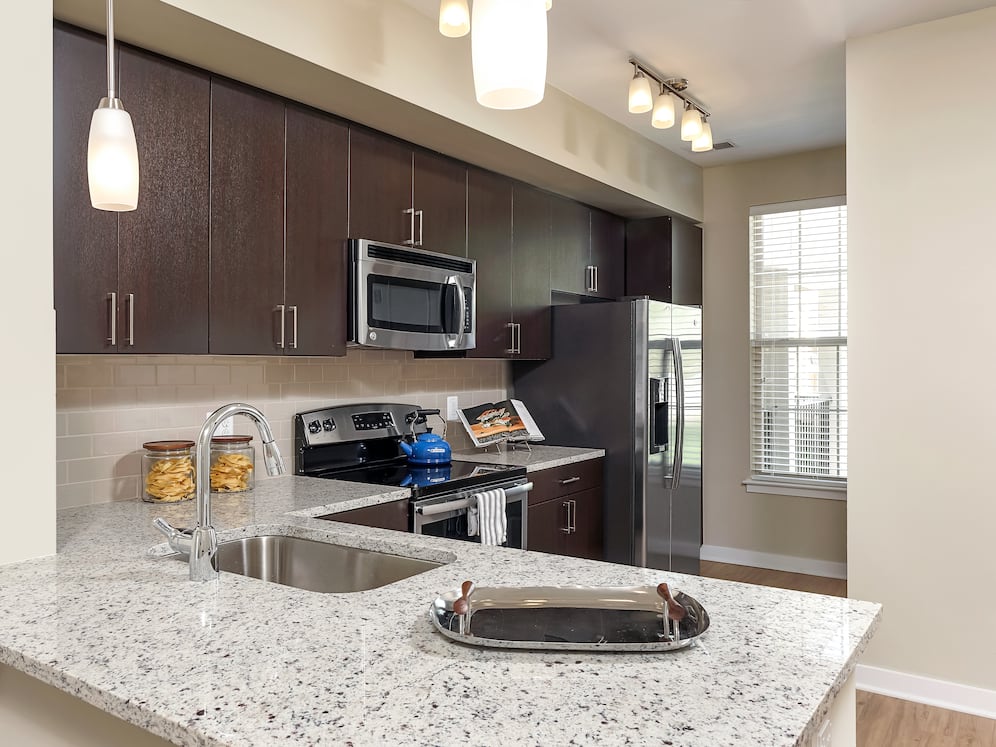 Classic Package II townhome kitchen with stainless steel appliances, espresso cabinetry, white speckled granite countertops, and hard surface flooring