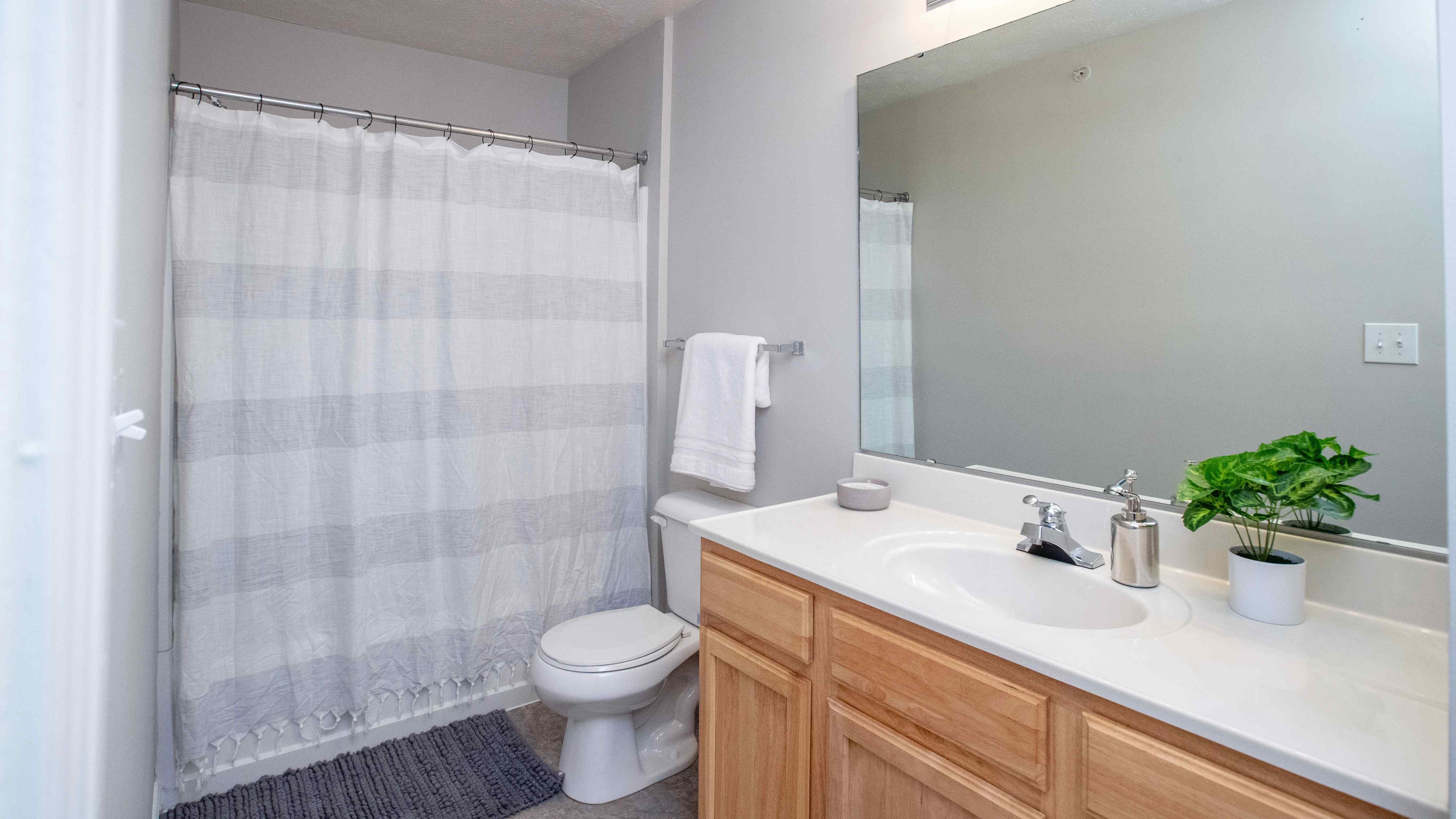 Bathrooms with wood-style flooring, spacious vanities, and oversized mirrors.