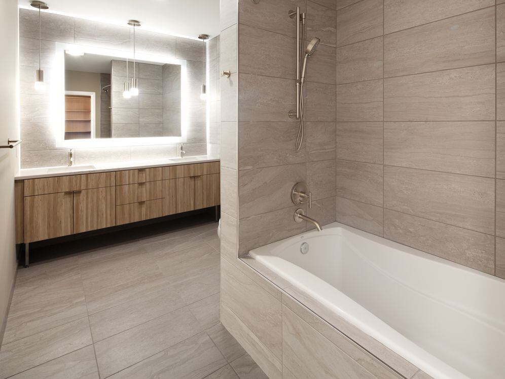 Signature Collection penthouse bath with oak cabinetry and white quartz countertop.