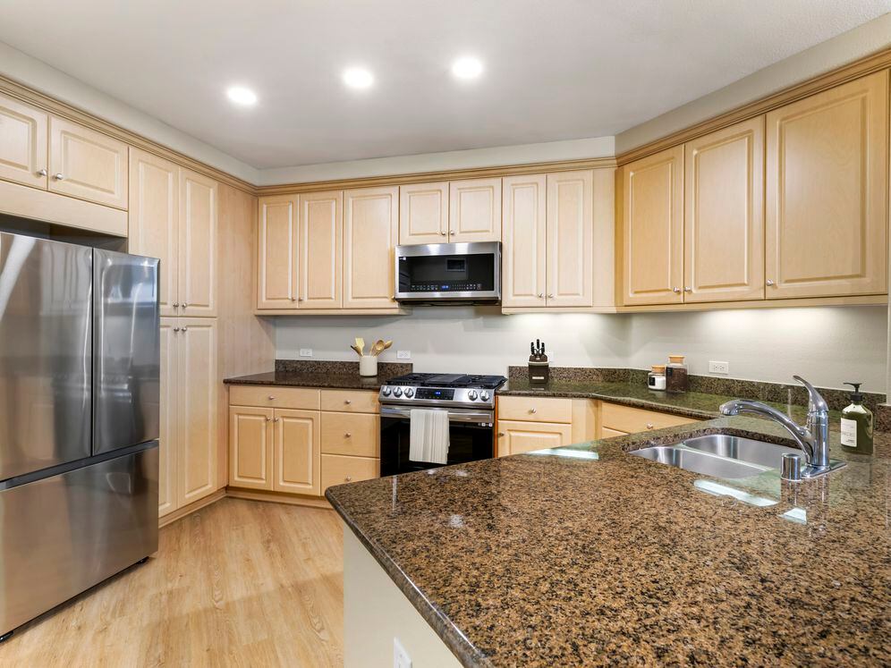 Classic Package II kitchen with stainless steel appliances, brown speckled granite, oak cabinetry, and hard surface flooring