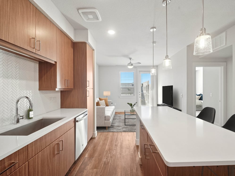 Finish Package I kitchen with stainless steel appliances, dark cabinetry, white tile backsplash, white quartz countertops, and hard surface flooring