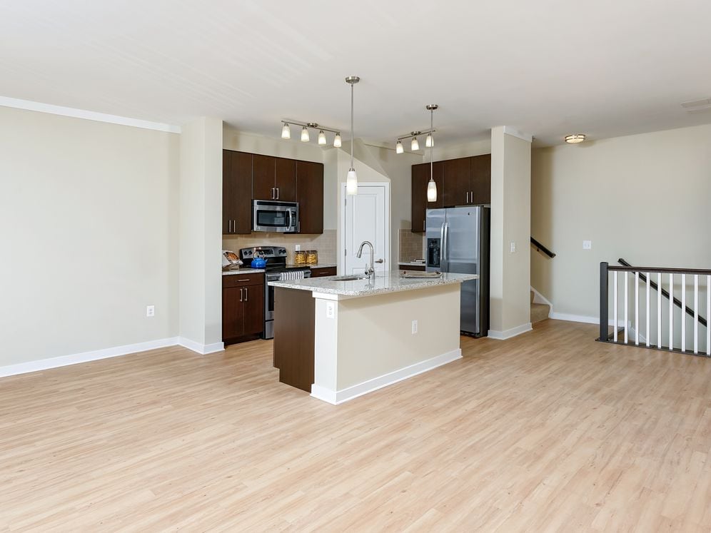 Living area and open concept kitchen with granite countertop, espresso cabinetry, stainless-steel appliances, kitchen island and hard surface flooring