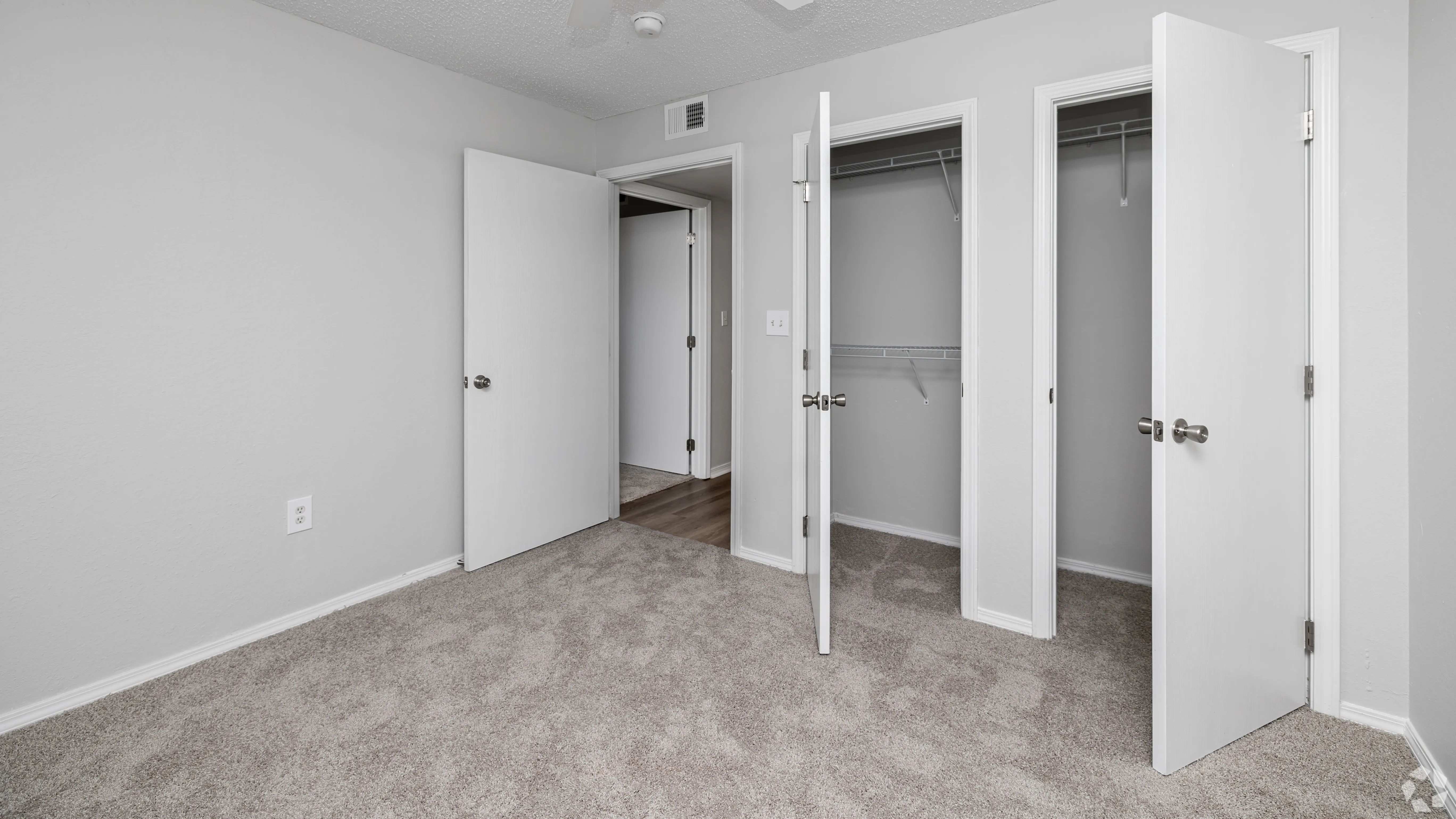 This bedroom at The Avenue features plush carpeting, bright natural light, and dual closets for added storage space.