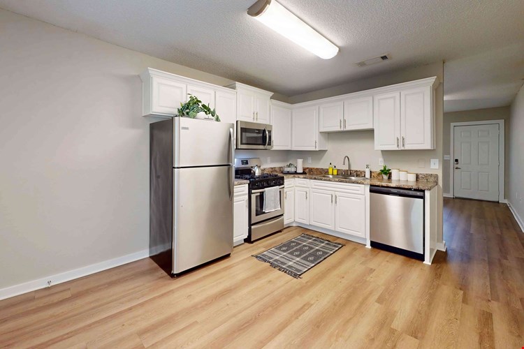 Experience the charm of a huge kitchen and dining area adorned with abundant white cabinetry and granite-inspired countertops for a delightful cooking and dining journey.