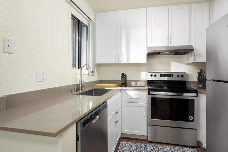 Renovated I kitchen with grey quartz countertops, white cabinetry, stainless steel appliances, and hard surface flooring