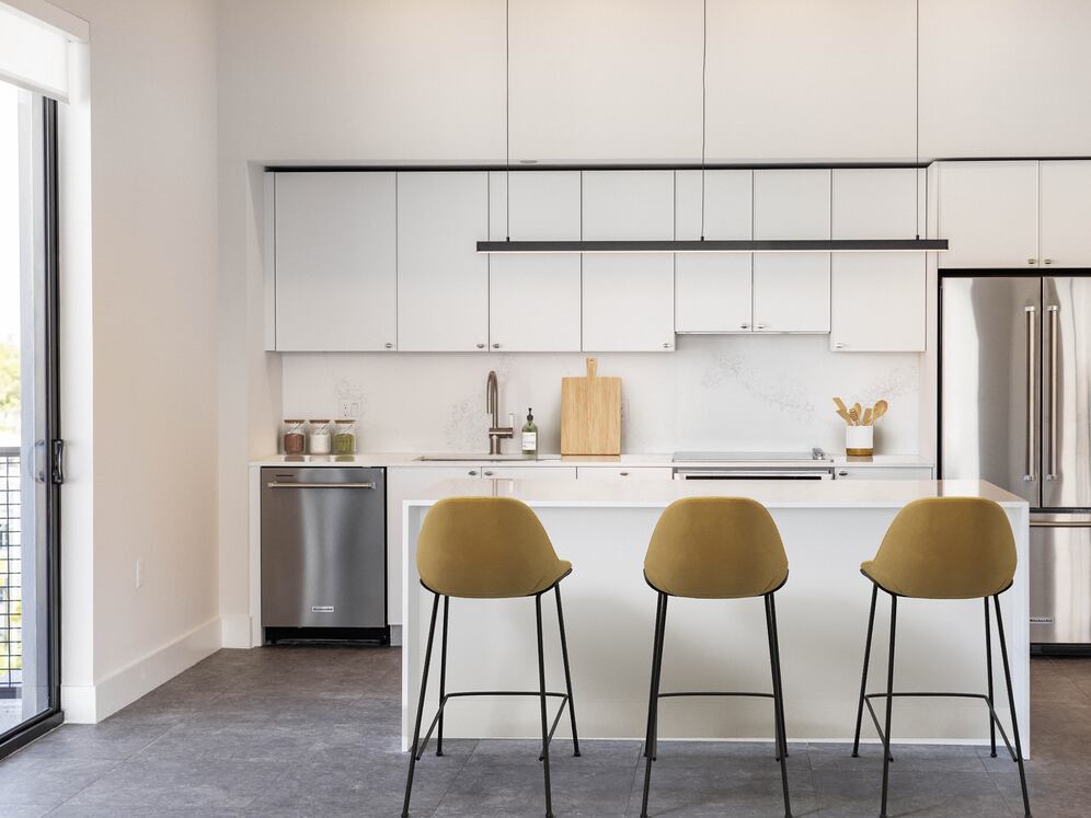 Signature Collection kitchen with white cabinetry, white marbled quartz countertop and backsplash, wine fridge, and upgraded stainless steel appliances