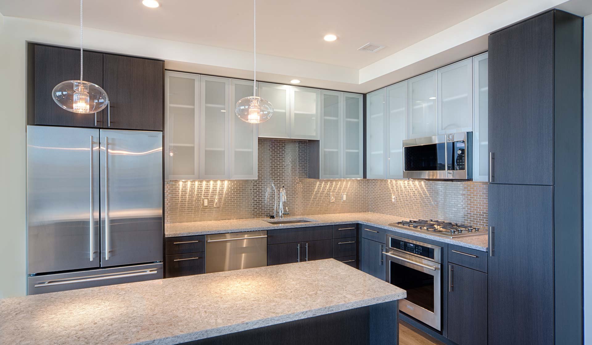 Penthouse kitchens feature frosted-glass cabinet doors, quartz countertops and breakfast bars