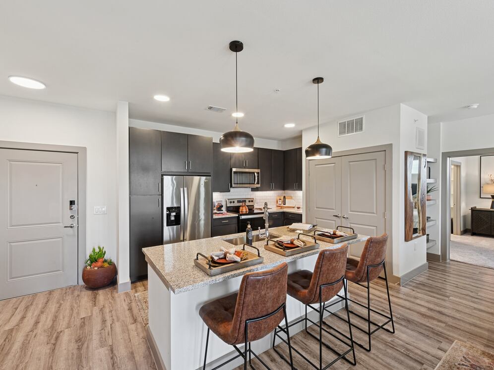 Kitchen with espresso cabinetry, speckled granite countertops, white subway tile backsplash, stainless steel appliances, and hard surface flooring