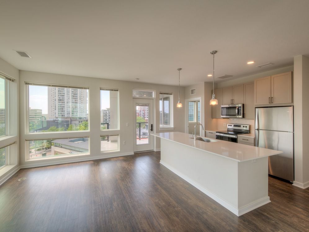 Scheme 2 kitchen and living area with floor to ceiling windows, quartz countertops, tile backsplash, stainless steel appliances and hard surface flooring