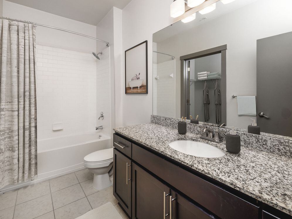 Classic Package II Bath with speckled granite countertop, dark wood cabinetry, and tile flooring