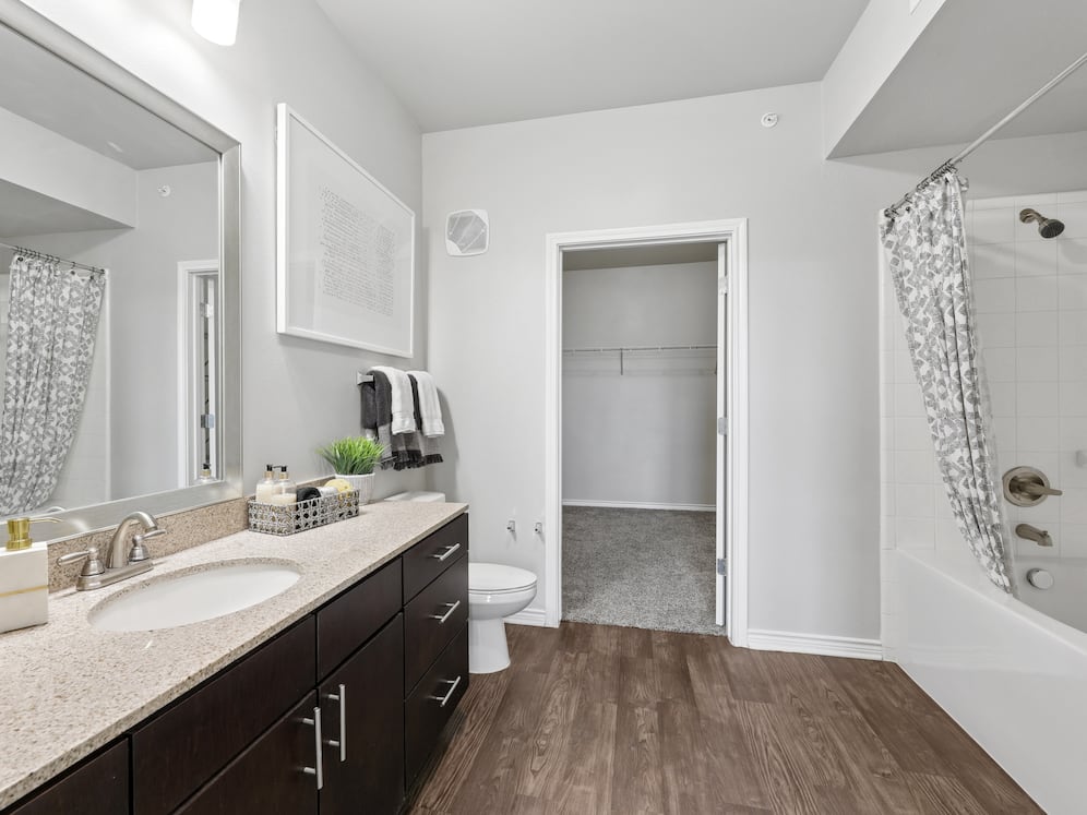 Bath with dark cabinetry, beige speckled granite countertops, and hard surface flooring