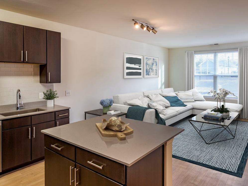 Newly renovated apartment homes feature kitchens with espresso cabinetry, grey quartz countertops, stainless steel appliances, grey tile backsplash, and hard surface flooring