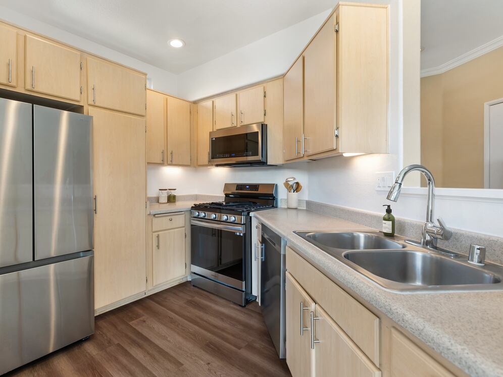 Updated Finishes kitchen with upgraded stainless steel appliances, laminate countertops, oak cabinetry, and upgraded hard surface flooring