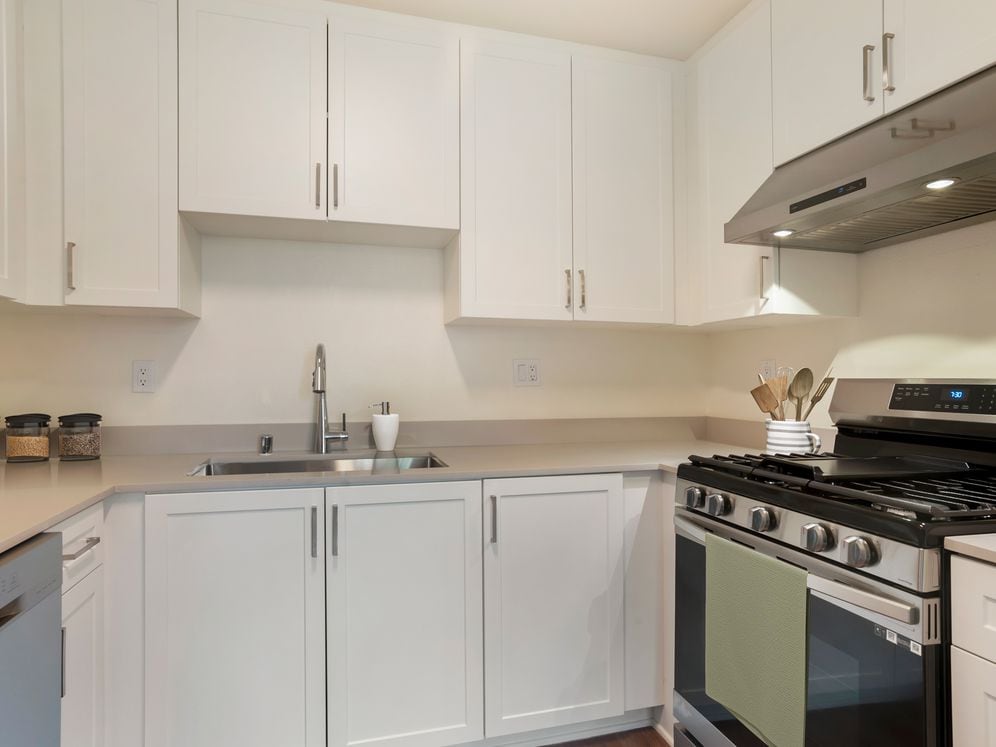 Renovated Package I kitchen with white cabinetry, beige granite countertops, stainless steel appliances, and hard surface flooring