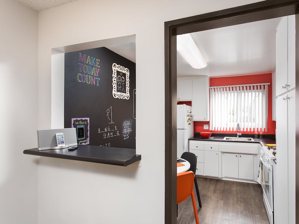 Classic Package II kitchen with white or black appliances, black laminate countertops, white cabinetry, and hard surface flooring (select homes)