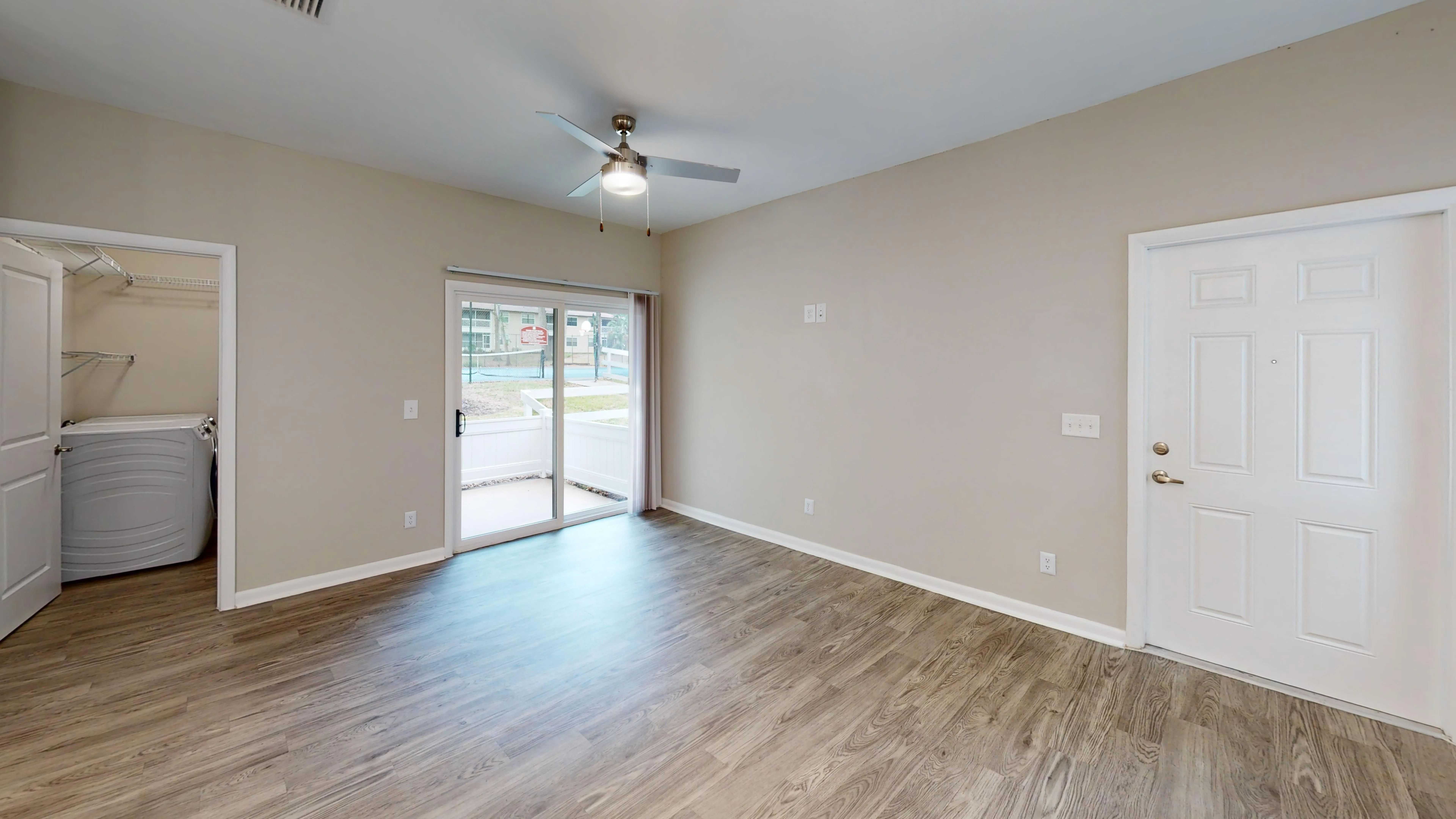 Enjoy the comfort of a spacious, open-concept living room in The Rosewood floor plan featuring wood-style flooring, abundant natural light, and direct access to a private patio.
