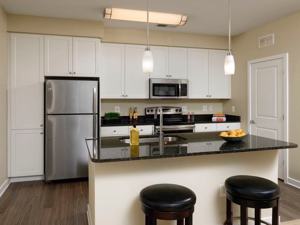 Open concept kitchen with white shaker cabinetry, granite countertops, kitchen island, stainless steel appliances and hard surface flooring