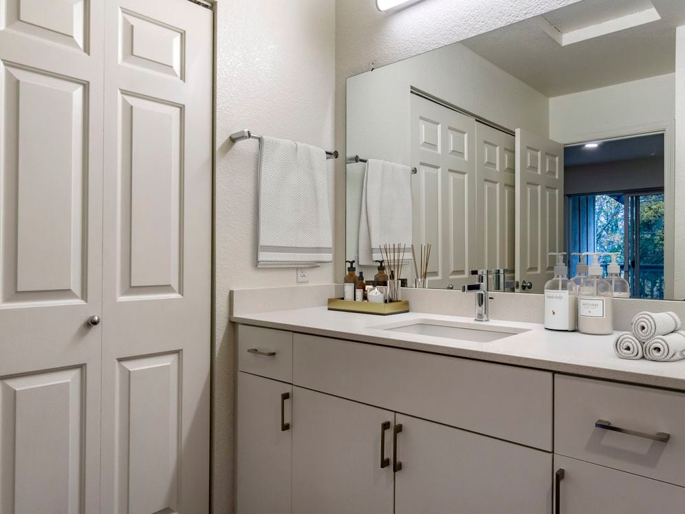 Renovated Package I bath with cream quartz countertops, white cabinetry, and hard surface flooring