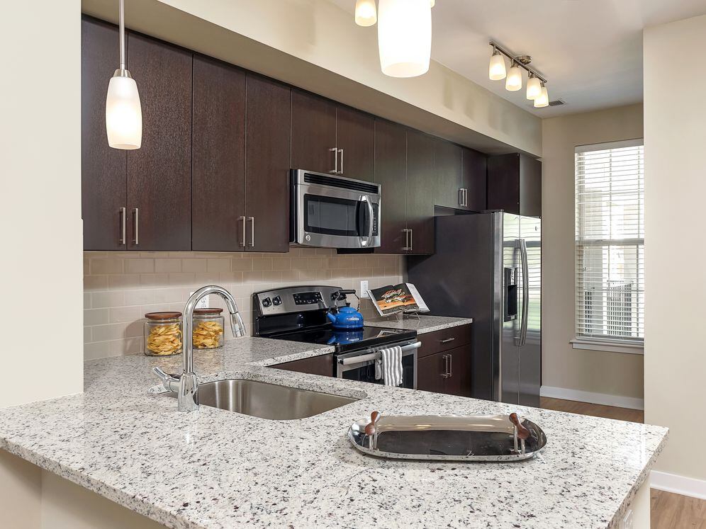 Kitchen with granite countertop, espresso cabinetry, stainless-steel appliances and hard surface flooring