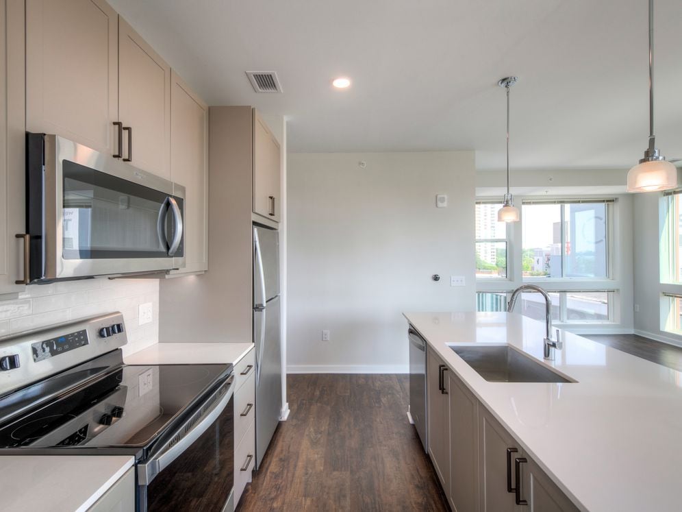 Scheme 2 kitchen and living area with floor to ceiling windows, quartz countertops, tile backsplash, stainless steel appliances and hard surface flooring