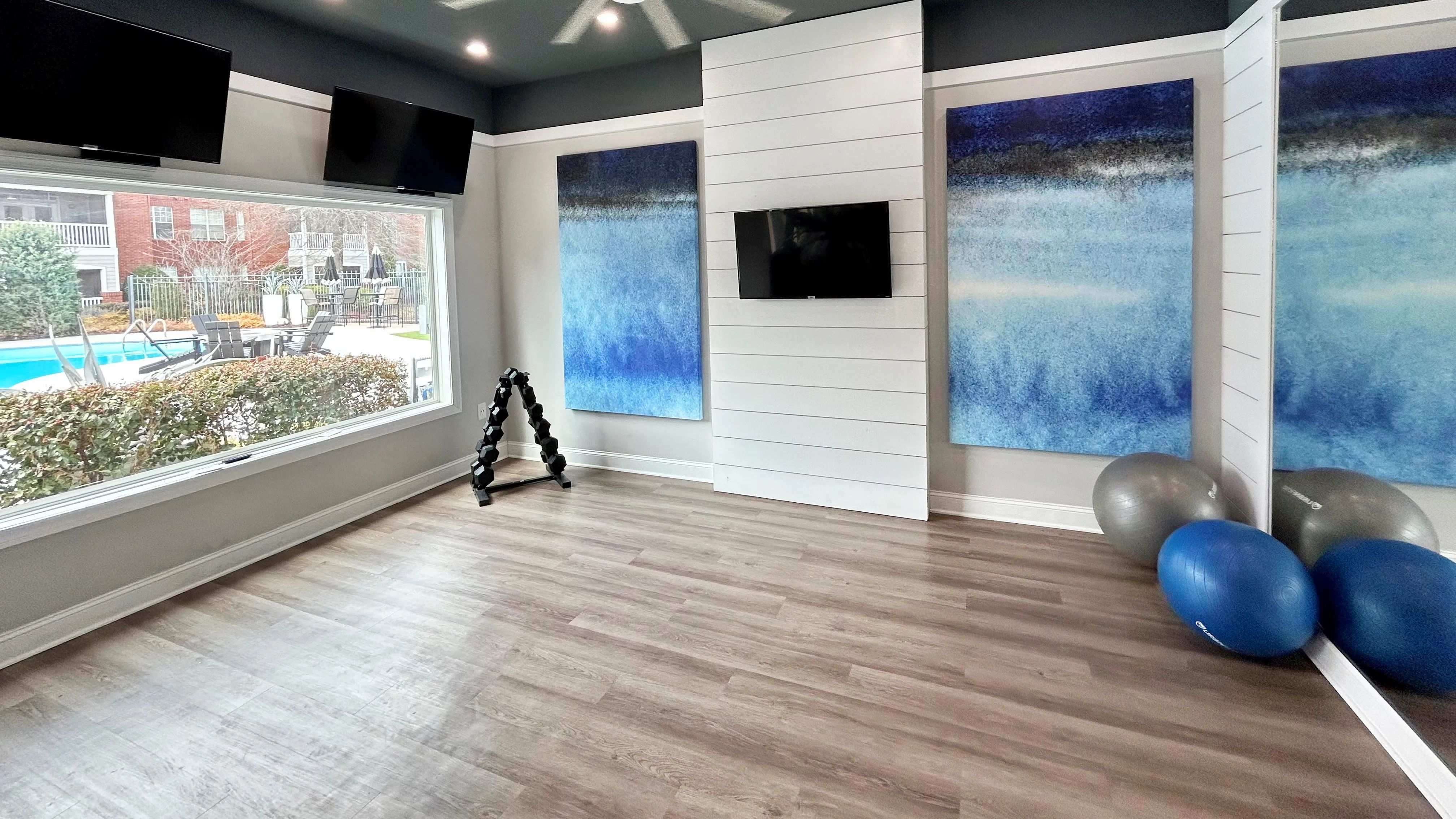 Find balance in our serene yoga studio, featuring a peaceful aesthetic, fitness balls, dumbbells, mirrored walls, and beautiful pool views.