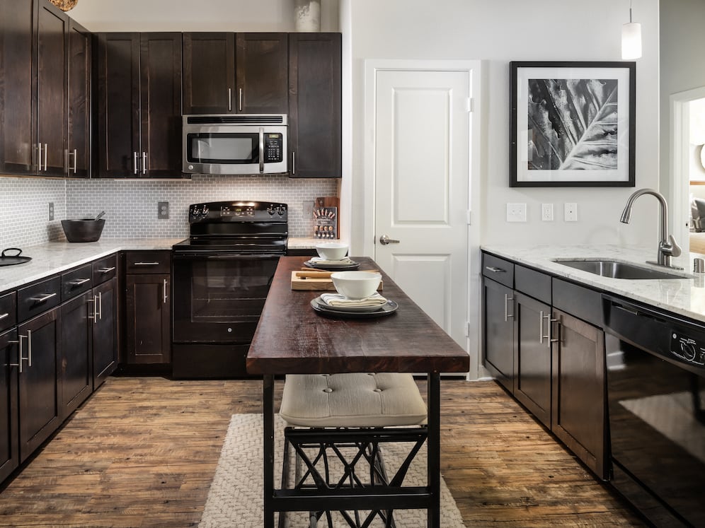 Kitchen with espresso cabinetry, granite countertops, tile backsplash, and hard-surface vinyl plank flooring