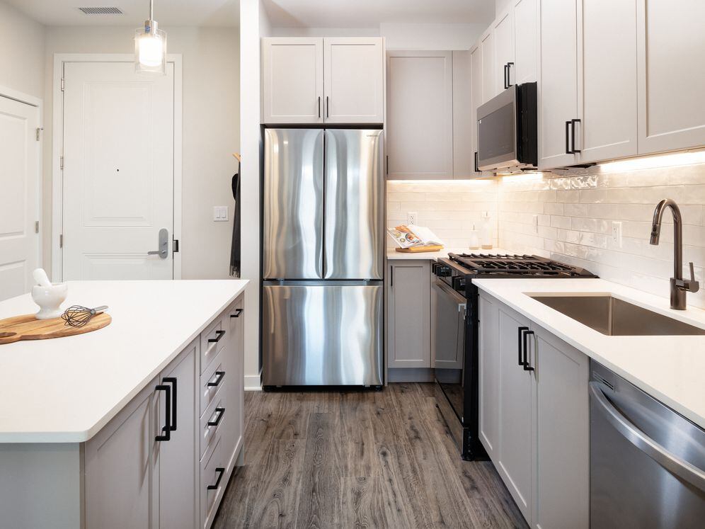 Modern with grey cabinetry, white quartz countertops, white tile backsplash, and stainless-steel appliances