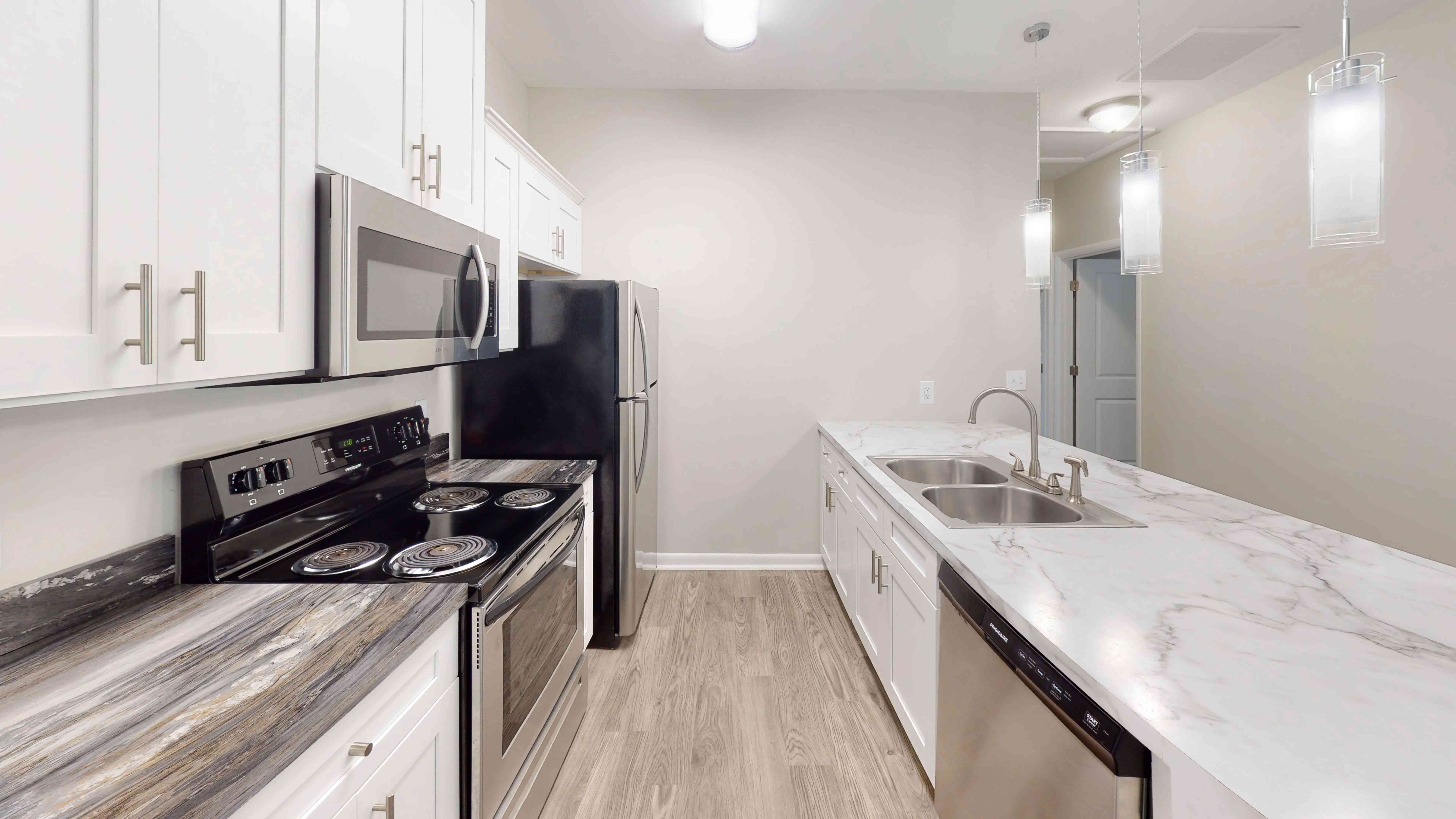 The Rosewood floor plan features a beautifully updated kitchenfeaturing a large island with a double-basin sink, stainless steel appliances, and contemporary finishes.