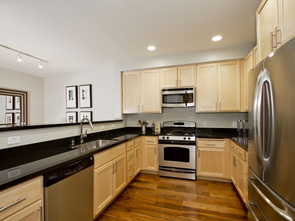 Townhome kitchen with oak cabinetry, stainless steel appliances, and hard surface flooring