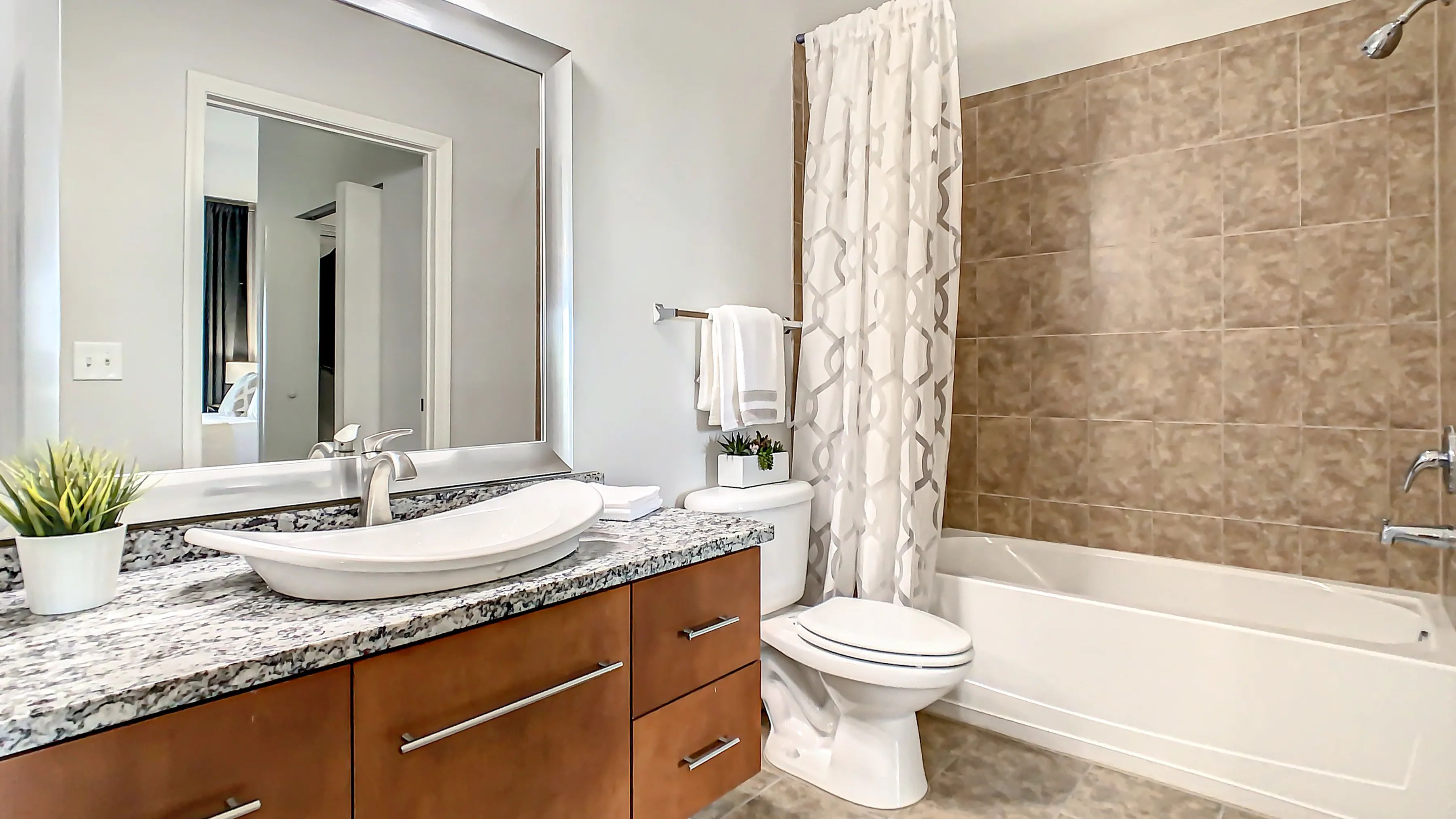 Our thoughtfully designed bathrooms boast considerable storage, fashionable framed mirrors, and spacious granite countertops with a modern bowl sink. 