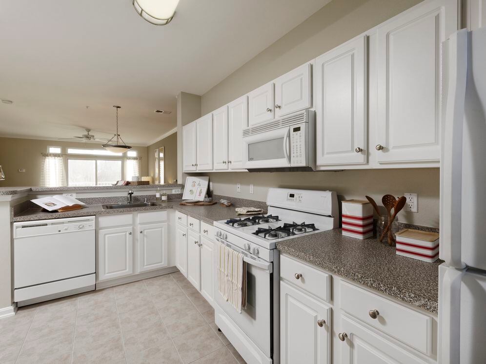 Classic Package I kitchen with white appliances, white cabinetry, laminate countertops, and vinyl tile flooring