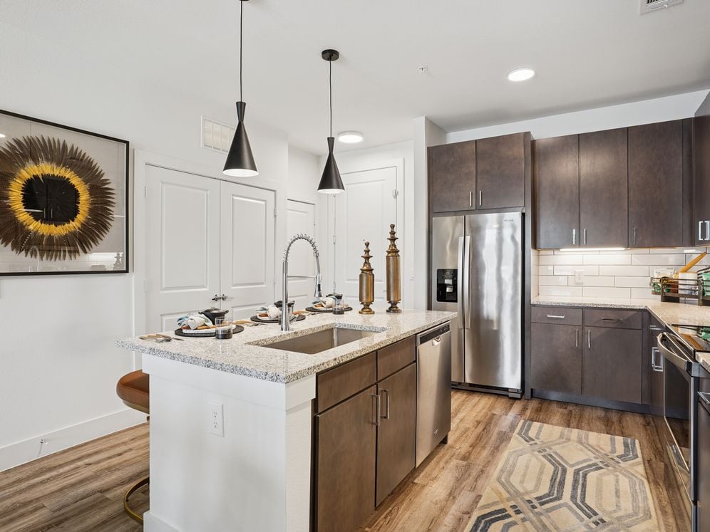 Kitchen with espresso cabinetry, speckled granite countertops, white tile backsplash, stainless steel appliances, and hard surface flooring