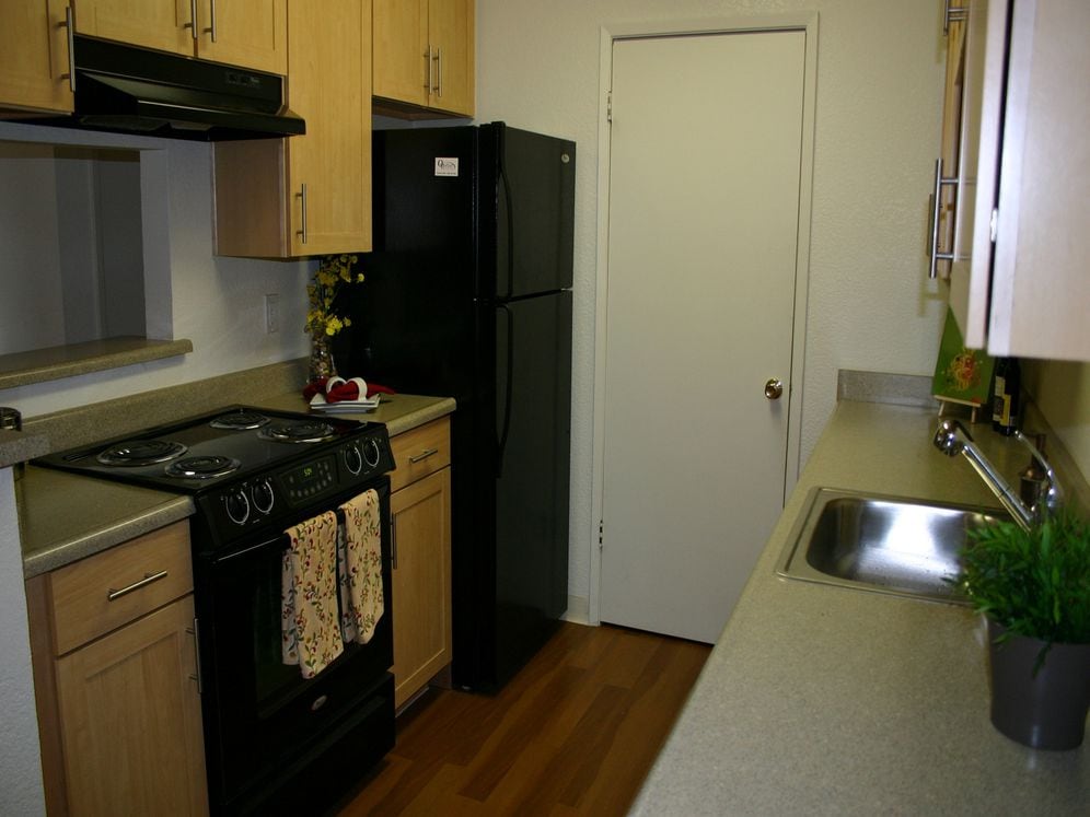 Kitchen with grey laminate countertop, black appliances, oak cabinetry and hard surface flooring