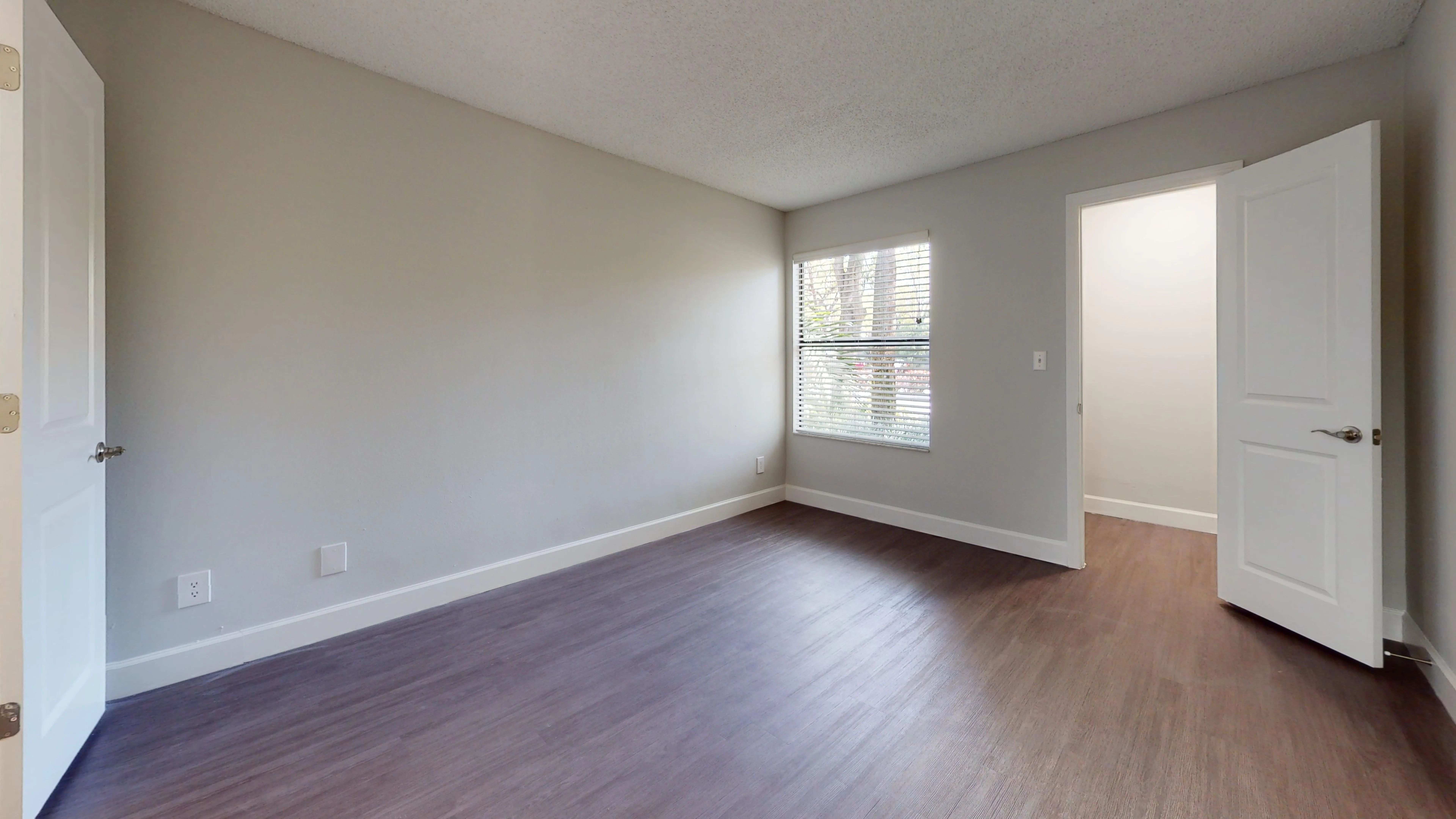 Experience comfort in the spacious bedroom featuring large windows for natural light and stylish wood-style flooring.