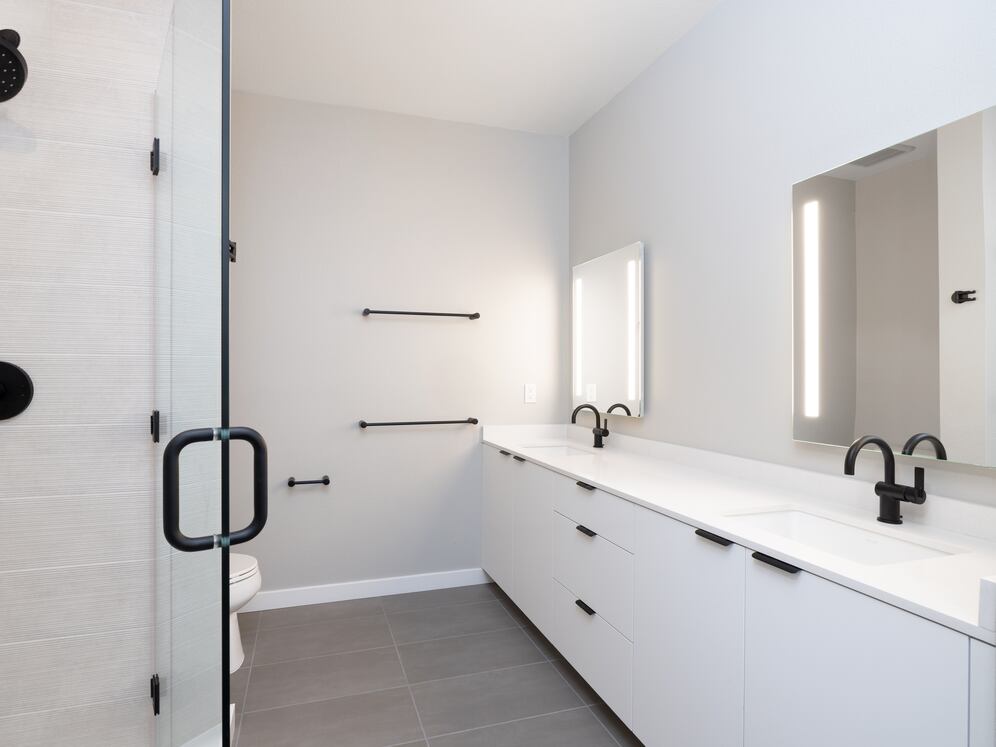 Signature Collection II Primary bath with dual vanity sinks, white cabinetry, LED lit mirror, white quartz countertops, and tile flooring