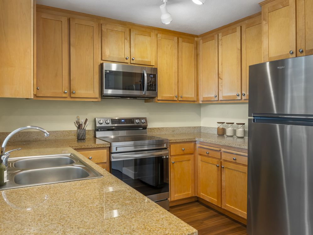 Classic Package II kitchen with oak cabinetry, beige speckled laminate countertops, stainless steel appliances, and hard surface flooring