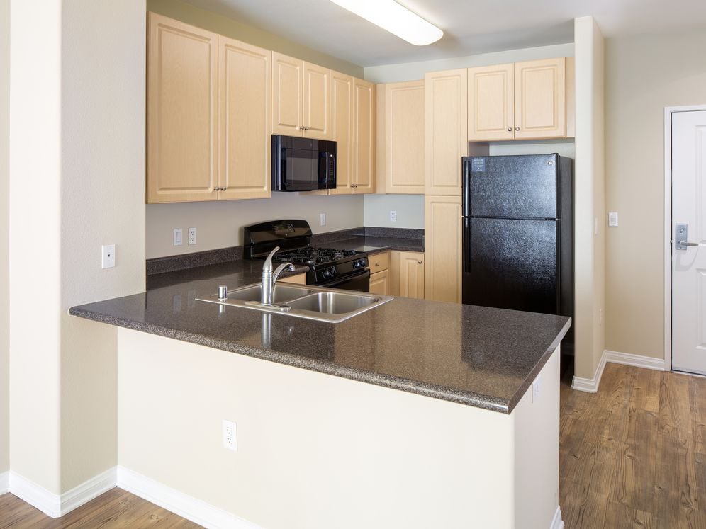 Kitchen with oak cabinetry, grey countertops, black appliances, and hard surface flooring