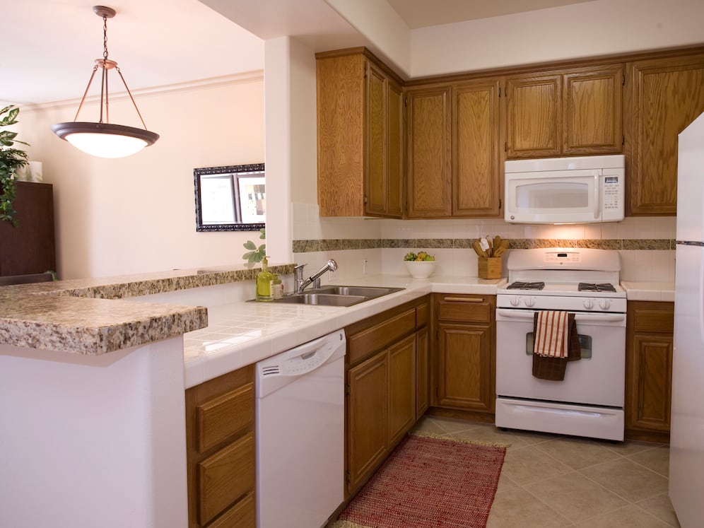 Classic Package I kitchen with white appliances, white tile countertop, oak cabinetry, and tile flooring