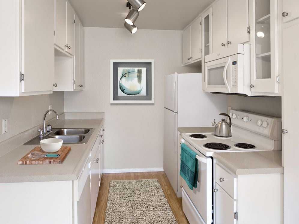 Classic Package I kitchen with beige laminate countertops, white cabinetry, white appliances, and hard surface flooring