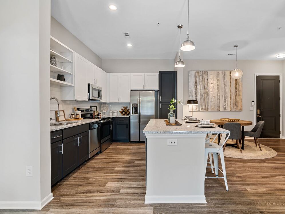 Kitchen with white and dark cabinetry, speckled granite countertops, white subway tile backsplash, stainless steel appliances, and hard surface flooring