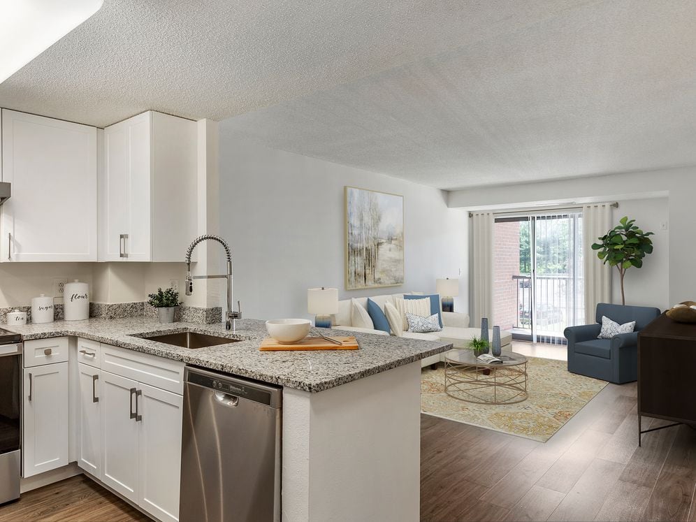 Renovated Package III kitchen and living area with white cabinetry, grey granite countertops, stainless steel appliances, and hard surface flooring