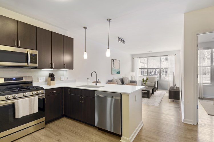 Renovated Package I kitchen with stainless steel appliances, white quartz countertops, espresso cabinetry, beige tile backsplash, and hard surface flooring