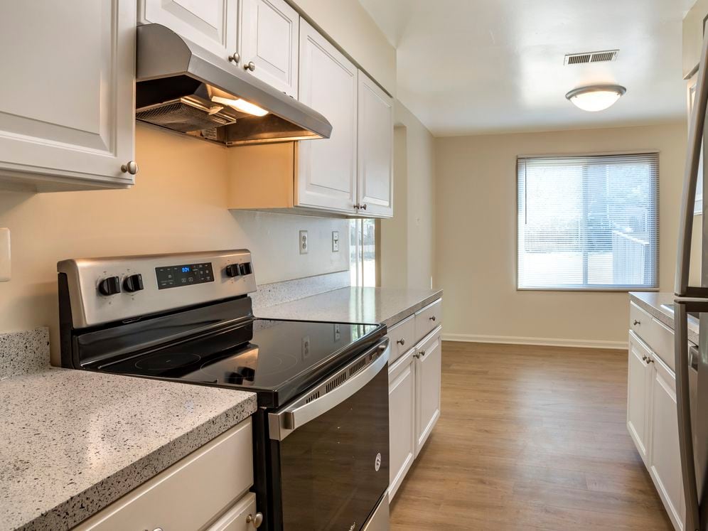 Renovated Package I kitchen featuring stainless steel appliances, white cabinetry, grey laminated countertops, and hard surface flooring