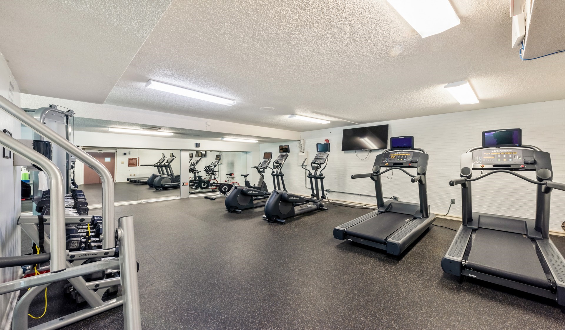 Fitness center with a variety of cardio machines and TVs mounted throughout