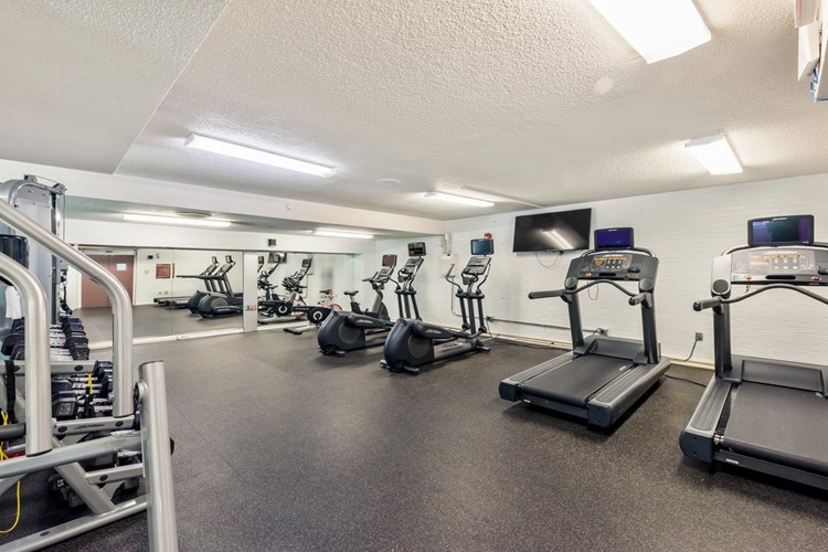 Fitness center with a variety of cardio machines and TVs mounted throughout