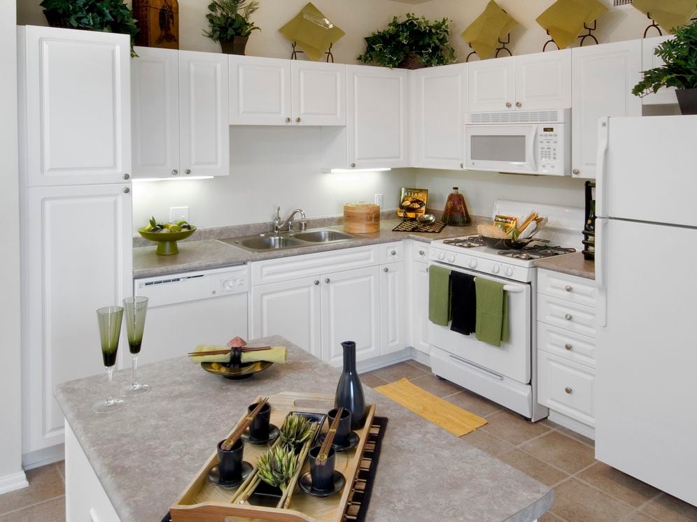 Classic Package I kitchen with island featuring white cabinetry, white appliances, laminate countertops, and tile flooring