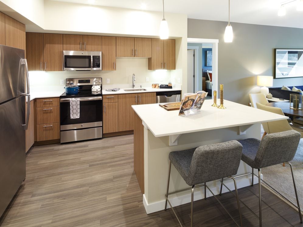 Phase I - Scheme B Kitchen with oak cabinetry, stainless appliances, white quartz countertops, and hard surface flooring