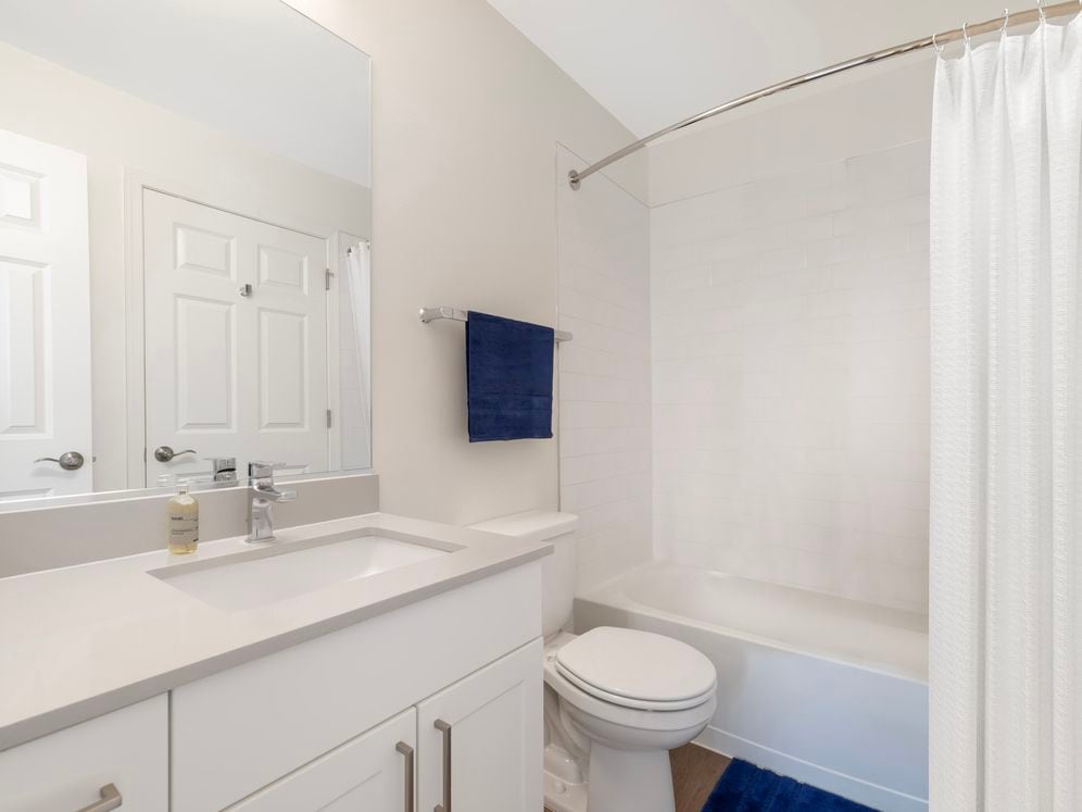 Renovated Package II bath with beige quartz countertop, white cabinetry, and hard surface flooring