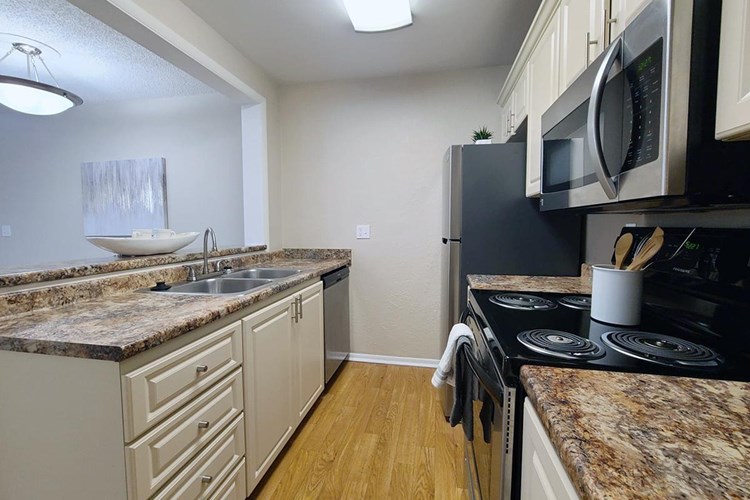 Our classic kitchen features granite-style countertops, wood-style flooring, and stainless steel appliances.