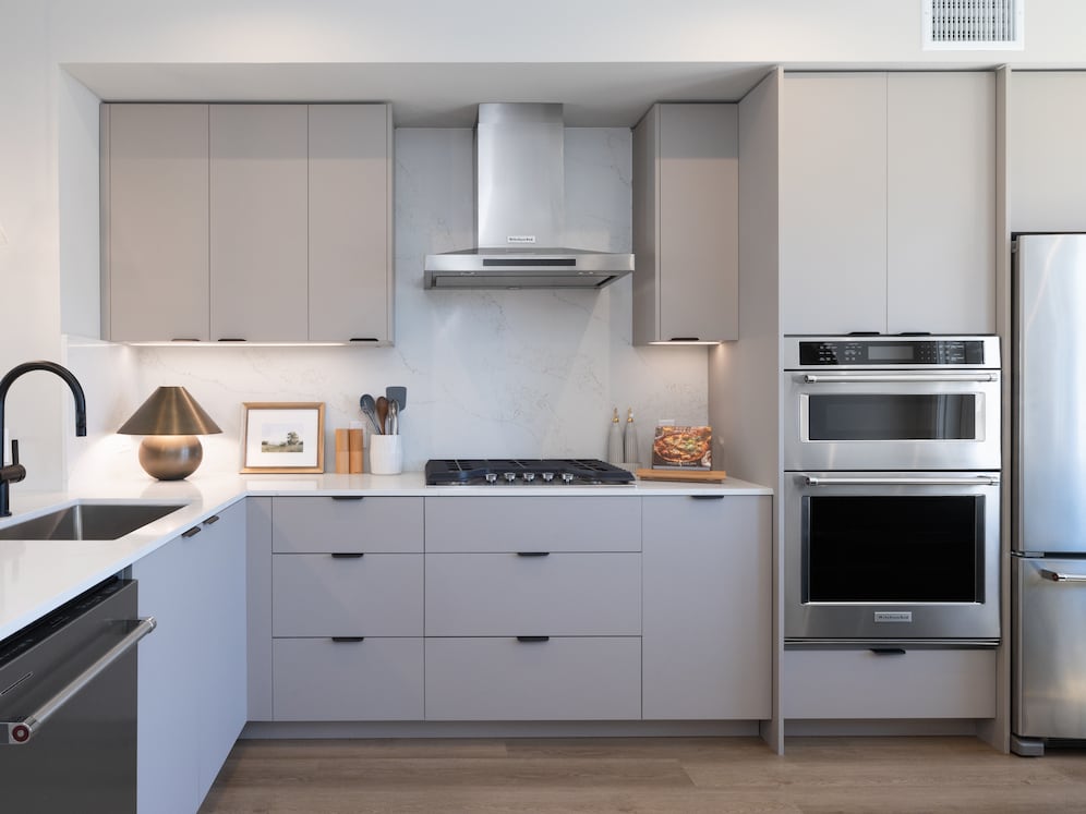 Signature Collection I 3-Bedroom Townhome Kitchen with light grey cabinetry, white marbled quartz countertops, and upgraded stainless steel appliances